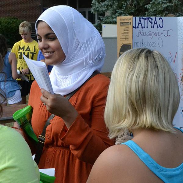 An international student provides information at a booth during 资本's welcome weekend